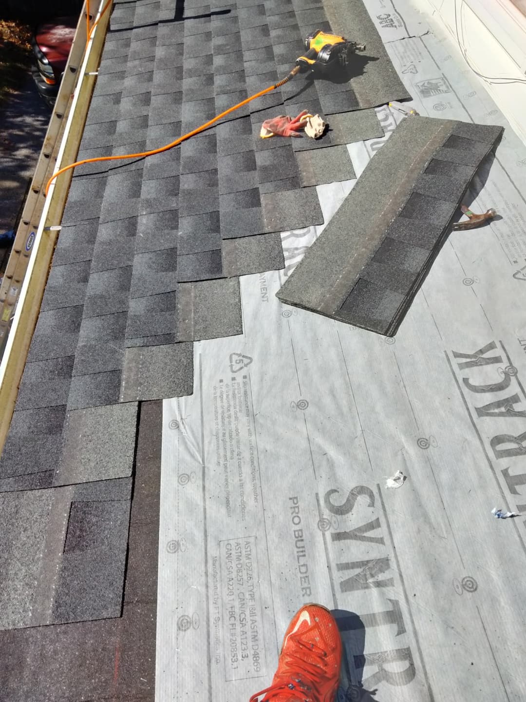 Picture of a new roof being installed and shingles being nailed in