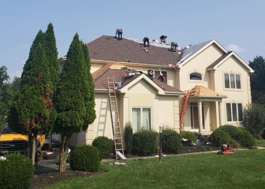 Roofers working on a roof of a two-story residential home